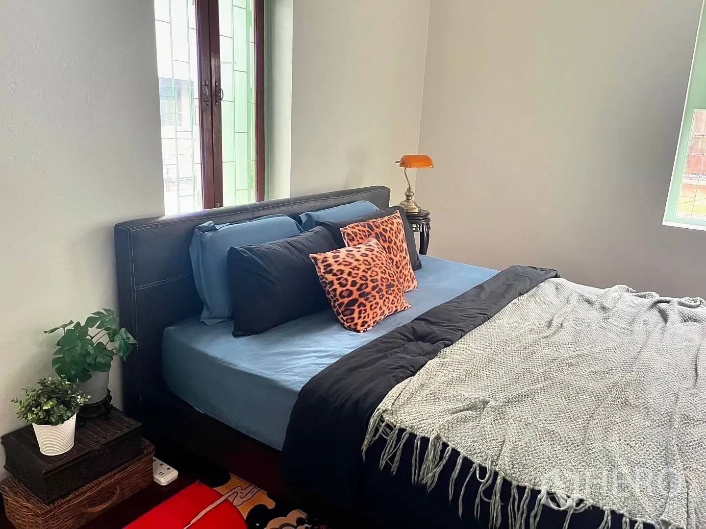 Shophouse for rent in Bang Rak, Bangkok - Cozy bedroom with upholstered bed, throw pillows, and greenery by windows.