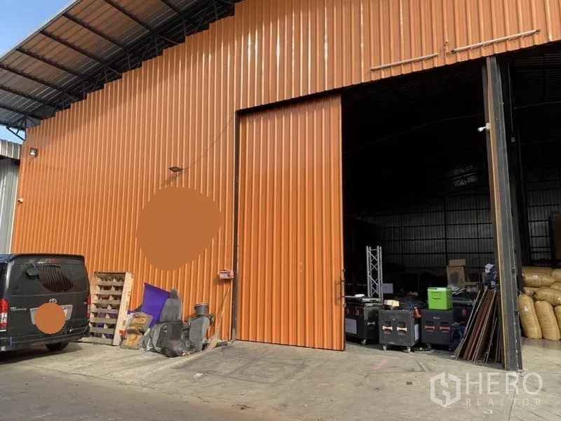 คลังสินค้า ให้เช่าในBang Kapi, Bangkok - ภายนอกโกดังผนังเมทัลชีทสีส้ม ประตูบานสไลด์ขนาดใหญ่และลานโหลดสินค้ามีหลังคา ในบางกะปิ