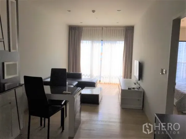 คอนโด ให้เช่าในBangkok - ห้องนั่งเล่นและรับประทานอาหารแบบโอเพ่นแปลน มีชั้นวางทีวี ชุดโต๊ะกินข้าว และประตูระเบียง ติดกับห้องนอน