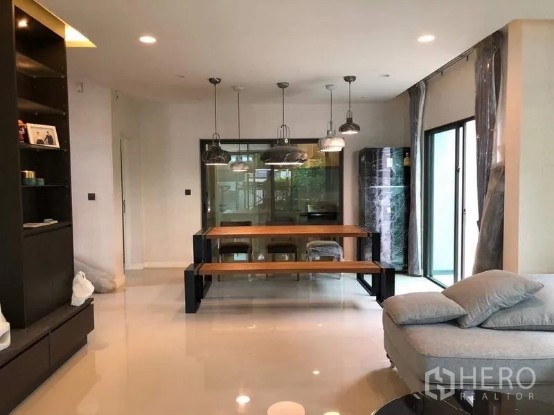 Detached House for rent in Bang Kapi, Bangkok - Bright dining area with long wooden table, four pendant lights and sliding glass doors to the patio.