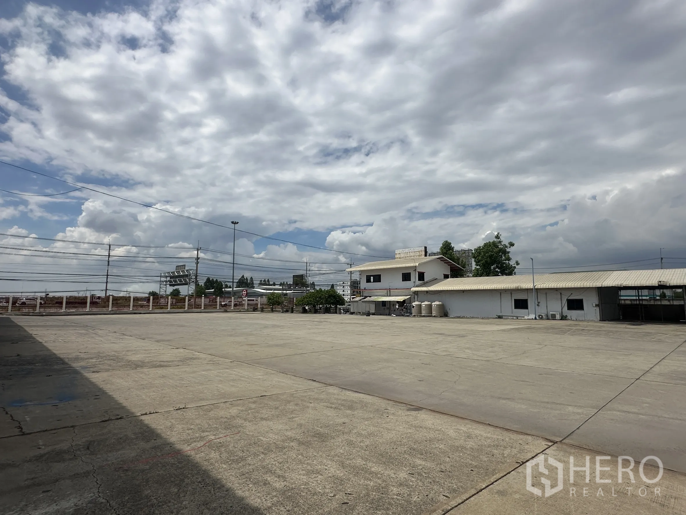 Land for rent in Wang Noi, Phra Nakhon Si Ayutthaya - Wide concrete parking and turning area facing single-storey site buildings.