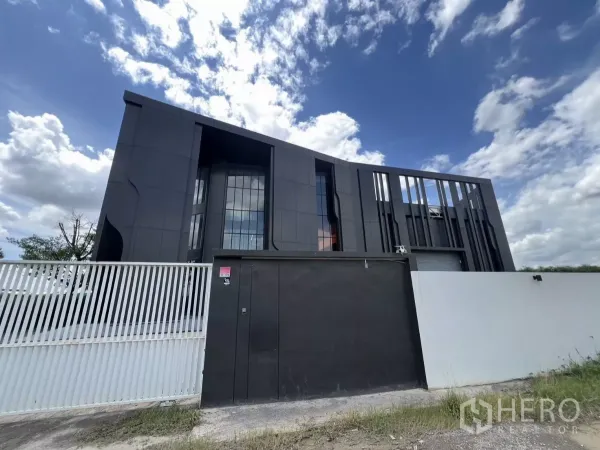 คลังสินค้า ขายในLat Krabang, Bangkok - ด้านหน้าคลังสินค้า–ออฟฟิศสไตล์โมเดิร์นสีดำ พร้อมประตูรั้ว ใต้ท้องฟ้าโปร่งในเขตลาดกระบัง.