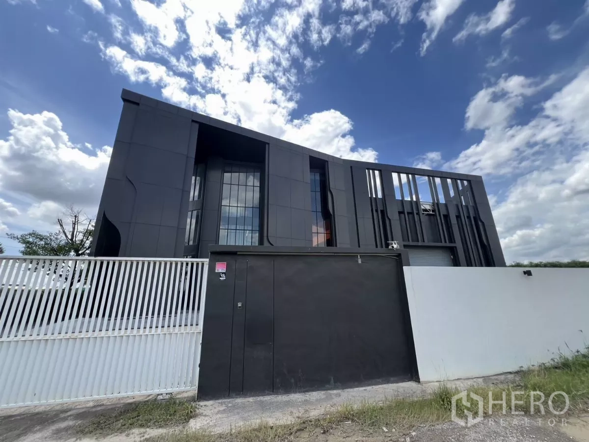 คลังสินค้า ขายในLat Krabang, Bangkok - ด้านหน้าคลังสินค้า–ออฟฟิศสไตล์โมเดิร์นสีดำ พร้อมประตูรั้ว ใต้ท้องฟ้าโปร่งในเขตลาดกระบัง.