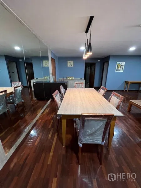 公寓 出租在Watthana, Bangkok - 餐厅设长桌六椅，镜面墙与吊灯，储物柜齐全。