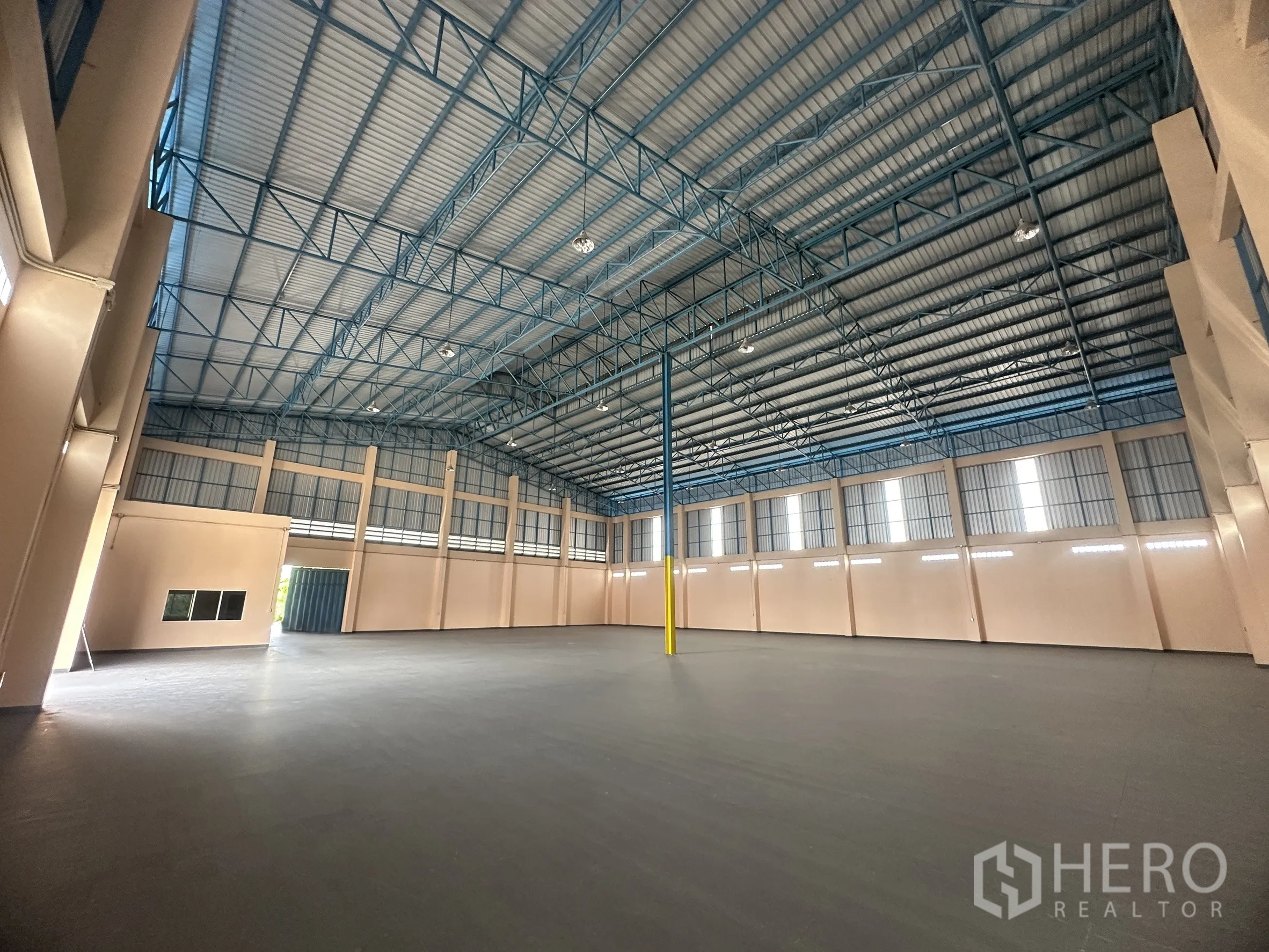 Warehouse for rent in Lat Lum Kaeo, Pathum Thani - Spacious warehouse interior with high steel truss roof, smooth floor, windows and a roller door.