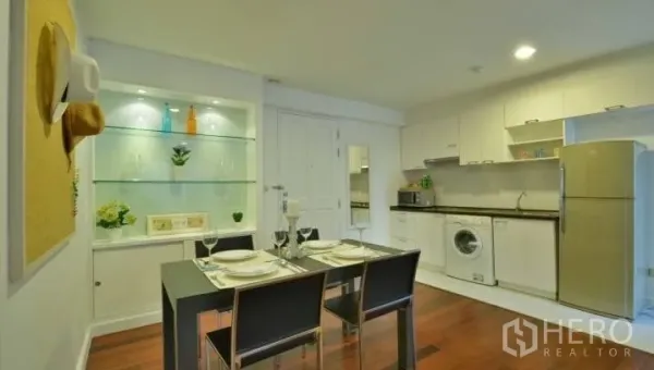Condominium for rent in Watthana, Bangkok - Dining space beside a compact kitchen with glass display shelves, cabinets and an in-unit washer.