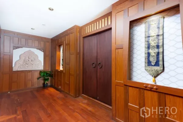 Condominium for rent or sale in Ratchathewi, Bangkok - Thai-inspired hallway with rich wood wall panels, carved niche and double doors.