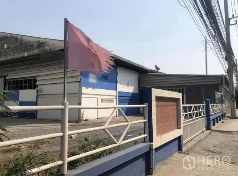 货栈 出租在Bang Phli, Samut Prakan - 街景外观：蓝白色仓库，带围栏与电线杆，位于邦帕里。