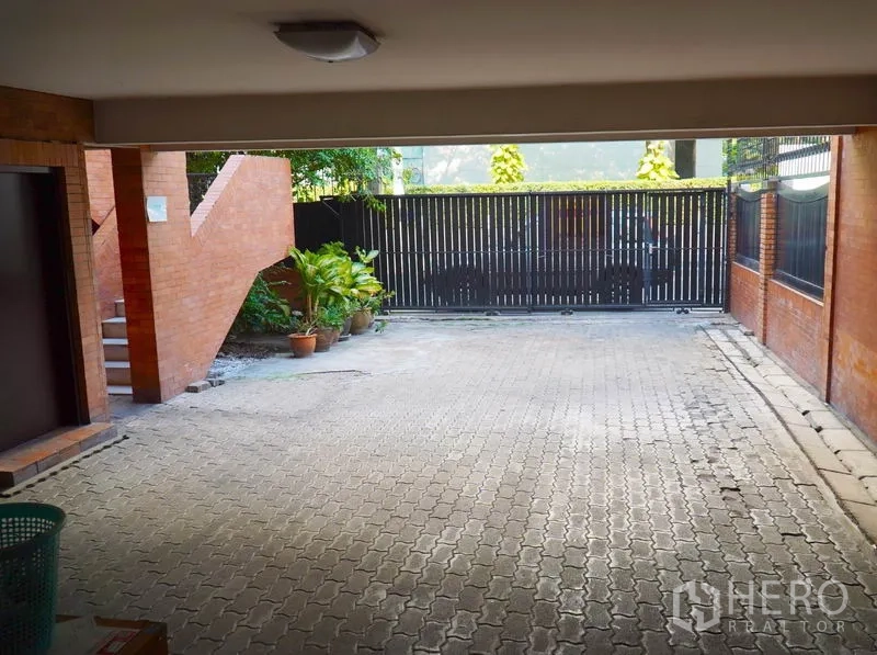 Townhouse for rent in Pathum Wan, Bangkok - Covered driveway and carport behind a black metal gate.