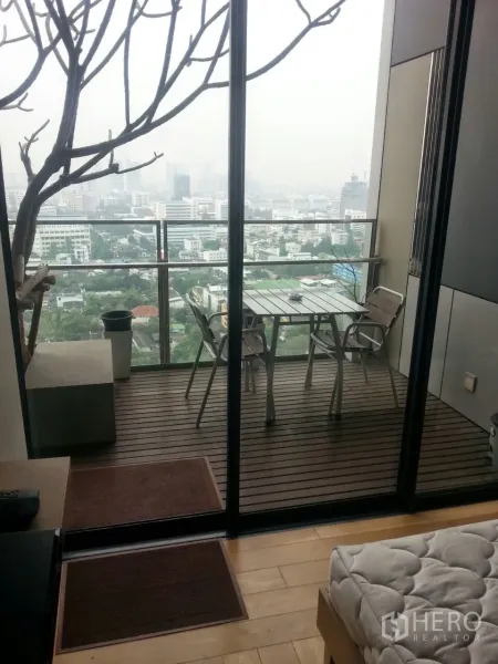 Condominium for rent or sale in Sathon, Bangkok - Private balcony with wood decking, outdoor table set and panoramic Bangkok skyline view.