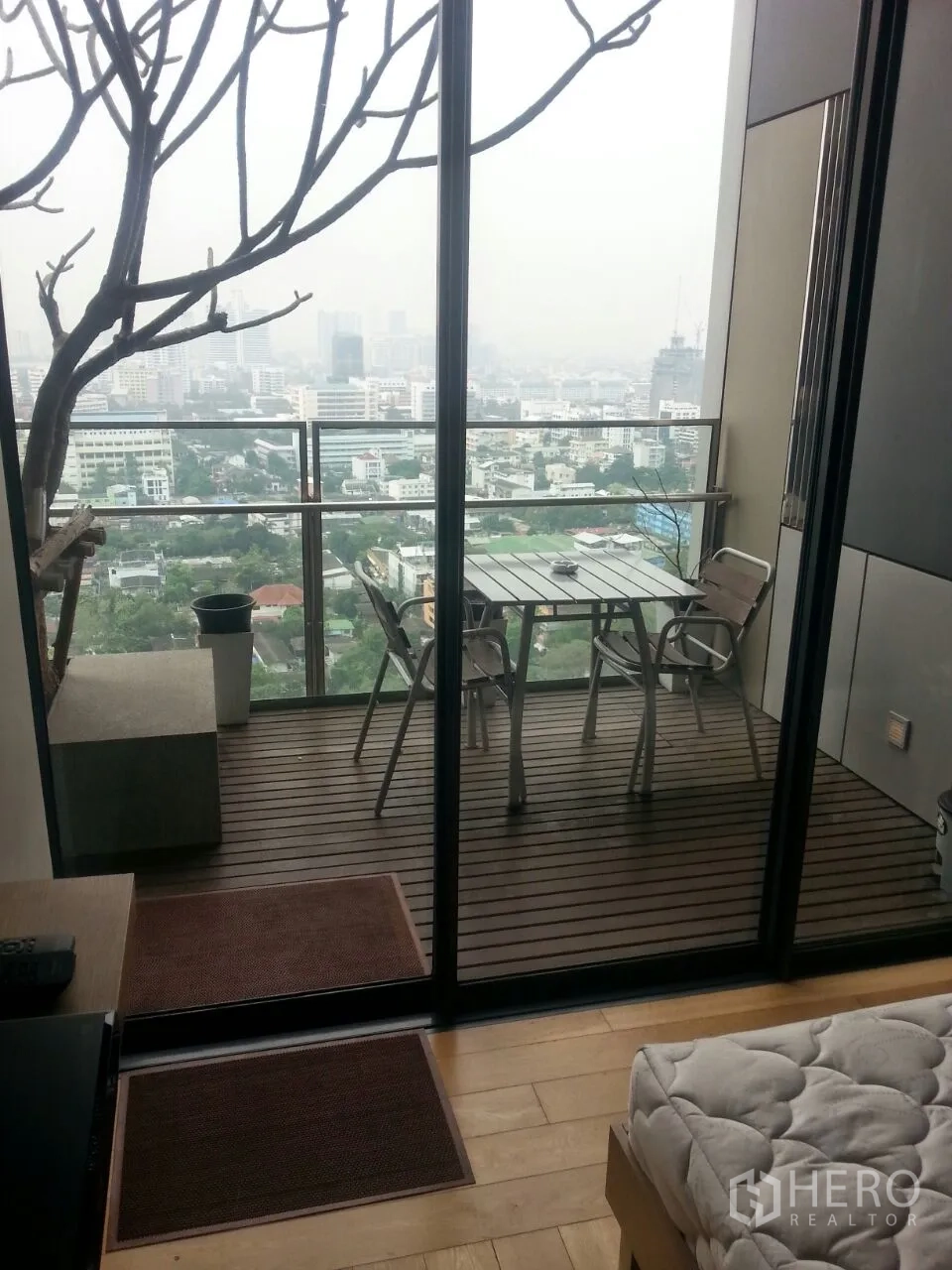 Condominium for rent or sale in Sathon, Bangkok - Private balcony with wood decking, outdoor table set and panoramic Bangkok skyline view.