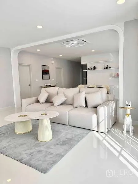 Detached House for rent or sale in Bang Phli, Samut Prakan - Bright living room with a white sofa, twin round coffee tables, arched feature and built-in shelves.