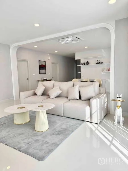 Detached House for rent or sale in Bang Phli, Samut Prakan - Bright living room with a white sofa, twin round coffee tables, arched feature and built-in shelves.