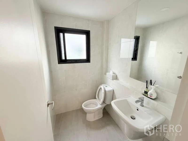 Detached House for sale in Bang Phli, Samut Prakan - Clean guest bathroom with window, sink and toilet in neutral tones.