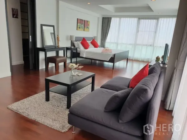 Apartment for rent in Bang Rak, Bangkok - Large bedroom-living layout with gray sofa, coffee table and wide windows.