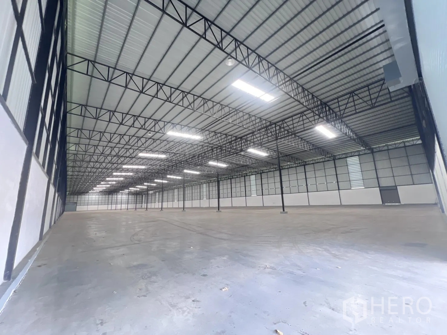 Warehouse for rent in Mueang Samut Sakhon, Samut Sakhon - Open warehouse interior showing steel roof trusses and smooth flooring.