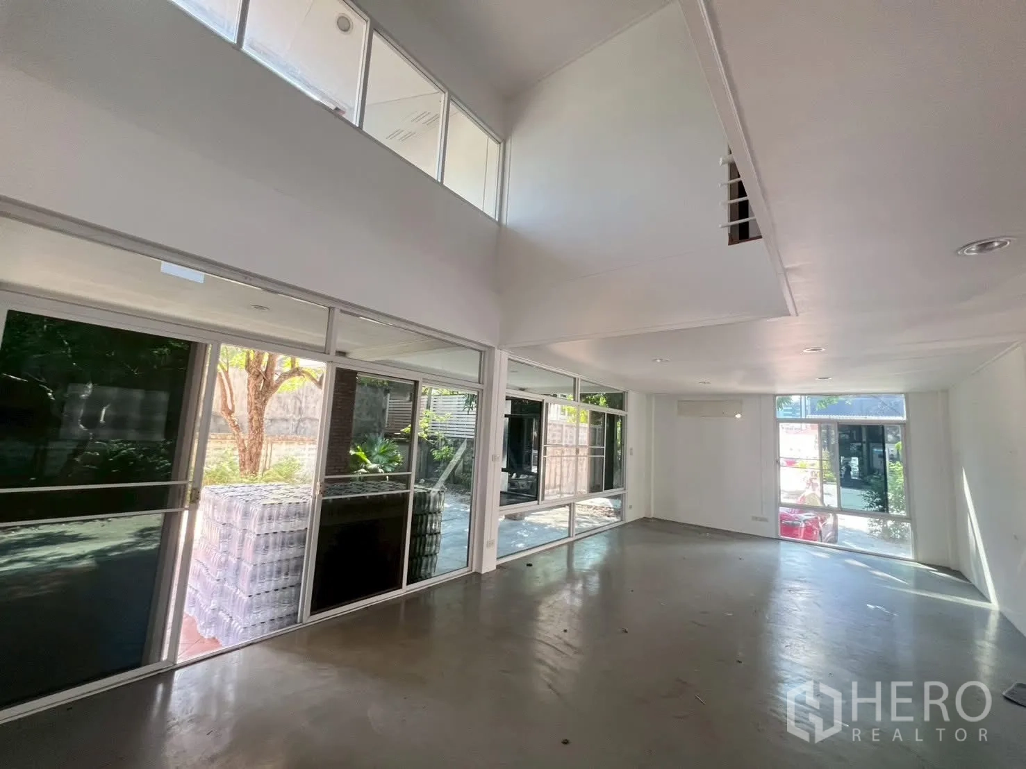 Detached House for rent in Watthana, Bangkok - Spacious living room with floor-to-ceiling windows facing the garden.