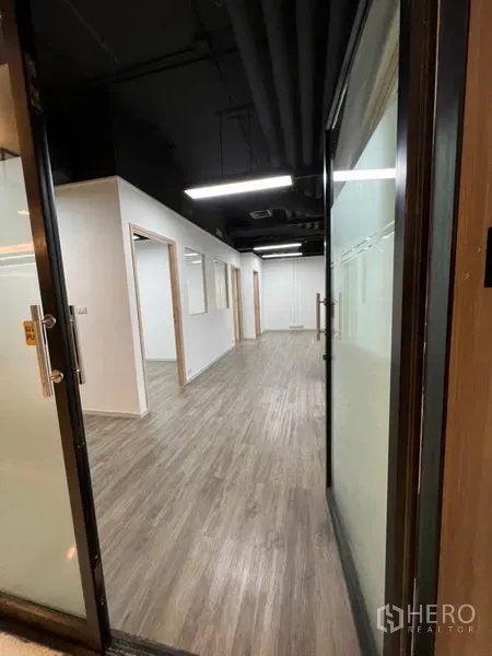 สำนักงาน ให้เช่าในKhlong Toei, Bangkok - มุมมองผ่านประตูกระจกสู่โถงออฟฟิศ พื้นลายไม้ เพดานสีดำ