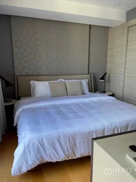 Condominium for sale in Pathum Wan, Bangkok - Cozy bedroom with a king-size bed, padded headboard and bedside lamps.