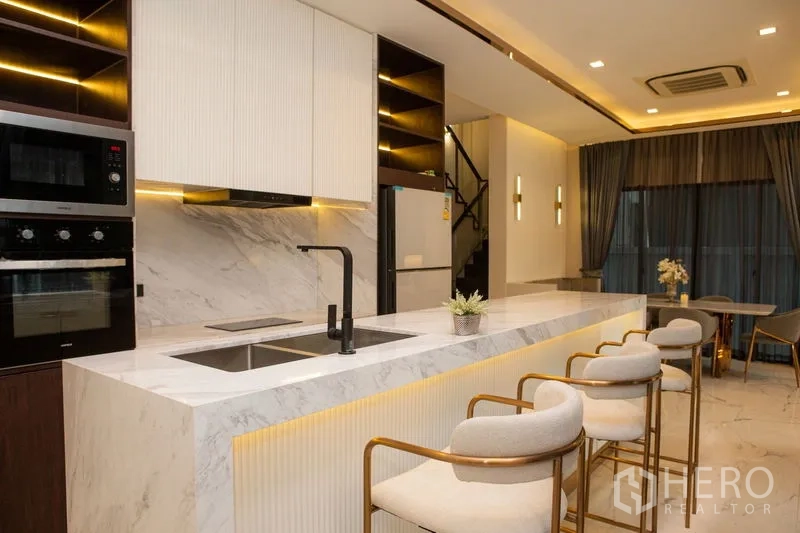 独立式住宅 出租或出售在Bangkok - 厨师级厨房，长条大理石中岛、吧椅与嵌入电器。