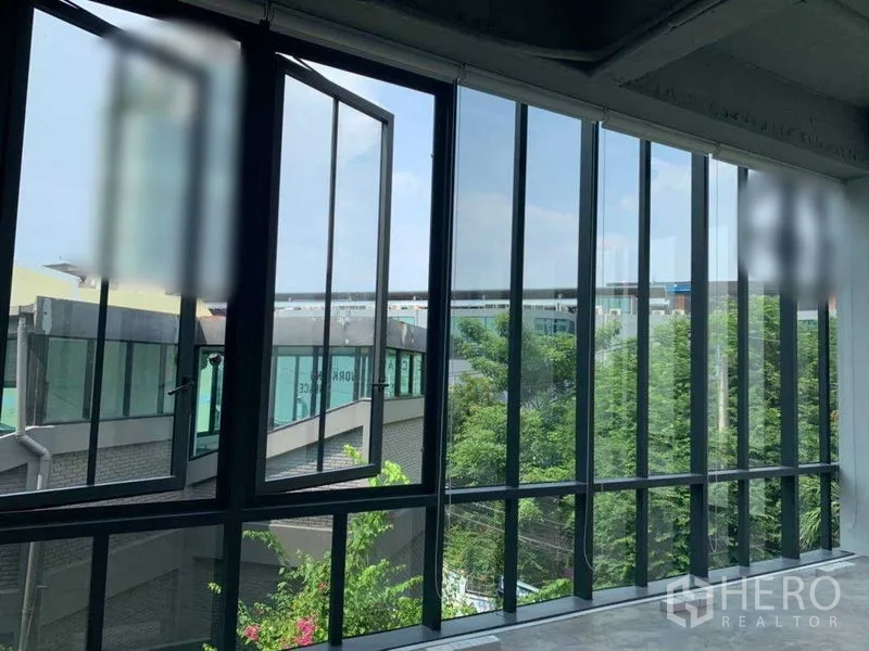 Office Space for rent in Khlong Toei, Bangkok - Large glass windows facing modern neighboring buildings and treetops.