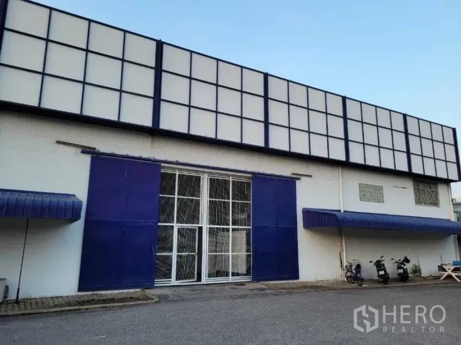 Warehouse for rent in Phra Khanong, Bangkok - Front entrance with blue sliding doors and a secure metal gate