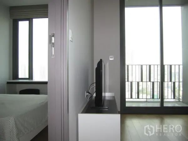 คอนโด ให้เช่าในKhlong Toei, Bangkok - ประตูกระจกบานเลื่อนเปิดสู่ระเบียงวิวเมือง ข้างชั้นวางทีวีและหน้าต่างห้องนอน