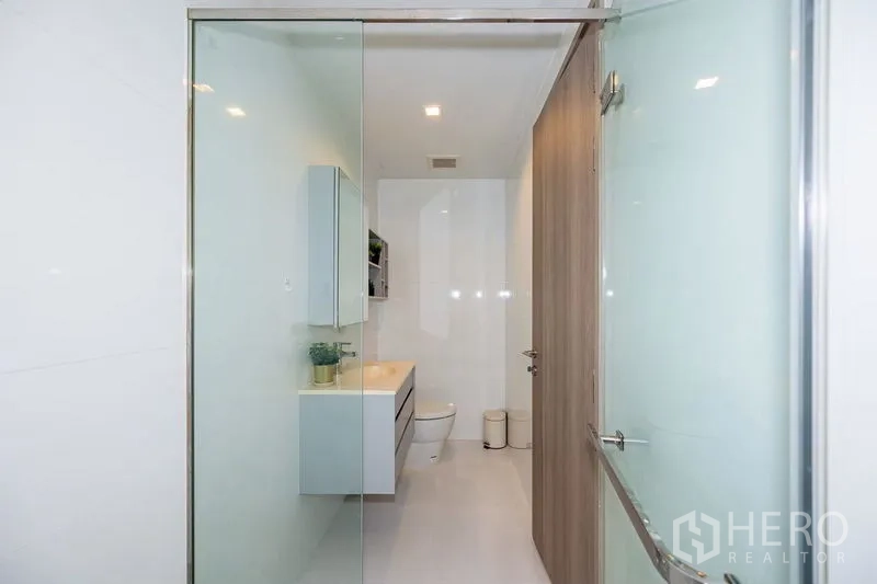 公寓 出租在Watthana, Bangkok - 从淋浴间望向盥洗台与坐便器的简洁白色浴室。