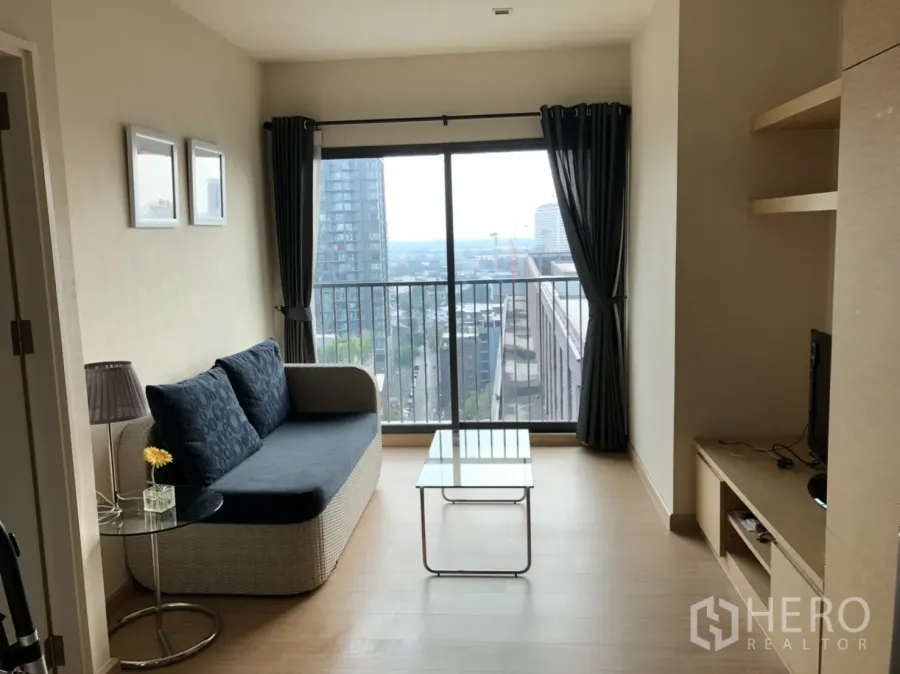 公寓 出租在Khlong Toei, Bangkok - 客厅采光充足，配沙发、电视柜与玻璃茶几，落地窗连通城市景观阳台，位于空堤区近BTS通罗。