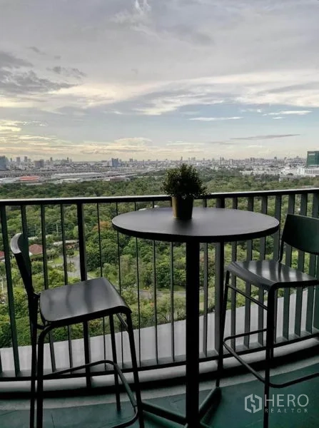 Condominium for rent - Evening balcony with high stools and plant pot, panoramic city and park view.