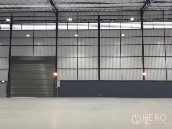 คลังสินค้า ให้เช่าในKhlong Sam Wa, Bangkok - พื้นที่ภายในโกดัง เพดานสูง ผนังเมทัลชีท ประตูม้วนขนาดใหญ่ และพื้นคอนกรีตขัดมัน