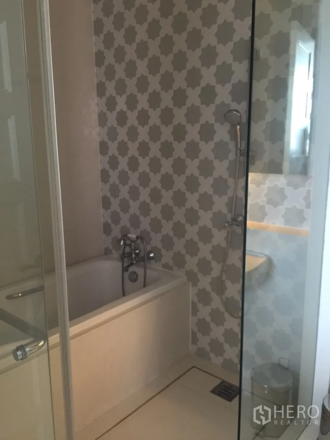 公寓 出租在Khlong Toei, Bangkok - 浴室带浴缸与手持花洒，几何纹墙面和玻璃隔断。