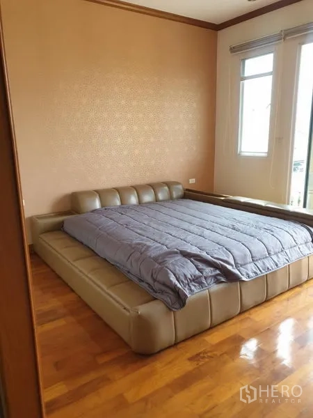 Townhouse for rent in Bang Kho Laem, Bangkok - Bedroom with low platform bed, parquet floor and twin windows.