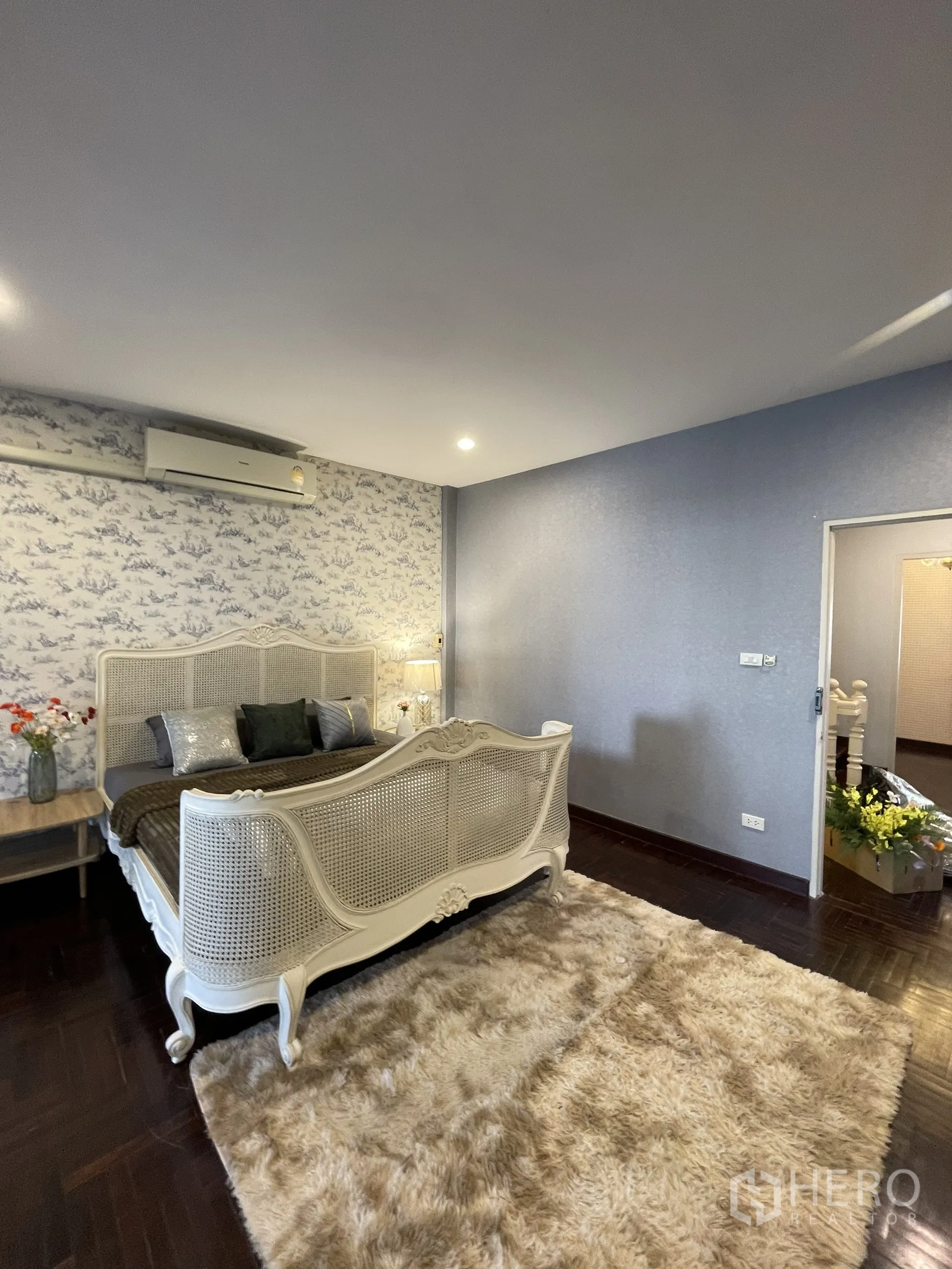 Shophouse for rent in Bang Kapi, Bangkok - Cozy bedroom view showing wallpapered feature wall, air conditioning and bedside tables.