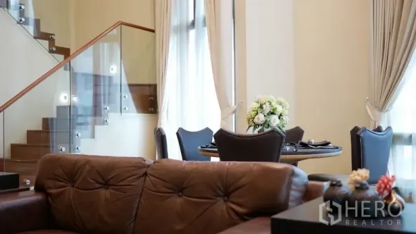 คอนโด ให้เช่าในKhlong Toei, Bangkok - ห้องนั่งเล่นพร้อมบันไดราวกระจก โซฟาบุหนัง และมุมทานอาหาร