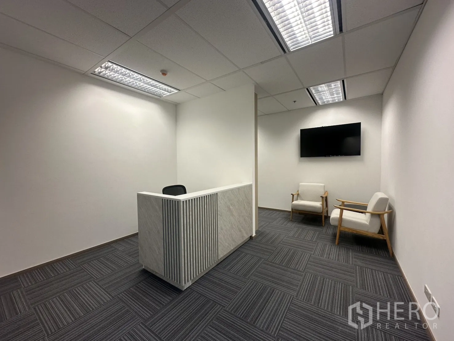 办公室 for rent in Pathum Wan, Bangkok - 接待区配大理石前台、壁挂电视与等候椅。