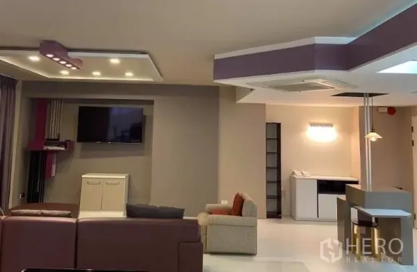 คอนโด ให้เช่าในWatthana, Bangkok - โซนนั่งเล่นพร้อมผนังทีวี ไฟตกแต่ง และที่นั่งหลายมุมโทนอบอุ่น