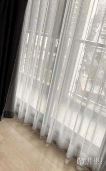 คอนโด ให้เช่าหรือขายในPathum Wan, Bangkok - หน้าต่างสูงจรดพื้นพร้อมผ้าม่านโปร่งและวิวเมืองรำไร