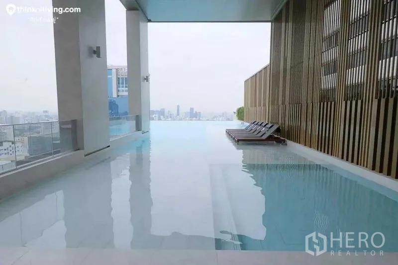 Condominium for rent in Watthana, Bangkok - Covered infinity swimming pool with city views and sun loungers