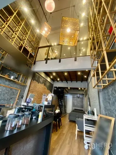 Shophouse for rent in Pathum Wan, Bangkok - Tall double-height space with hanging lanterns, display shelves and sofa seating leading to the rear zone.