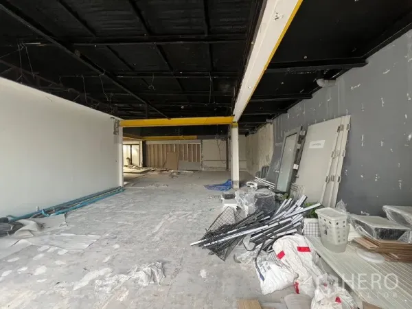 零售空间 出租在Watthana, Bangkok - 开放式室内施工中，黑色天花与黄色梁，水泥地面。