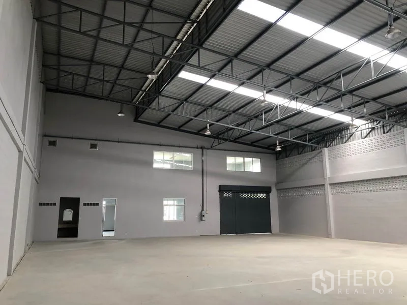 Factory for rent in Lat Lum Kaeo, Pathum Thani - Warehouse interior showing high-clearance roof, ventilation block walls and a large sliding steel door.