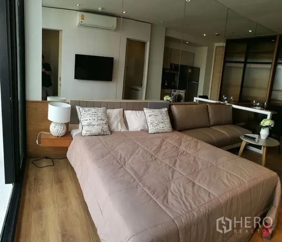 คอนโด ขายในKhlong Toei, Bangkok - ห้องนอนคอนโดสว่างด้วยหน้าต่างบานใหญ่ เตียง โซฟา ทีวีติดผนัง และพื้นไม้