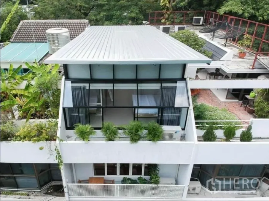 ทาวน์เฮาส์ ให้เช่าในKhlong Toei, Bangkok - ด้านหน้าทาวน์เฮาส์หลายชั้นสไตล์โมเดิร์น ผนังกระจกสูง หลังคาเมทัลชีทและต้นไม้ตกแต่ง