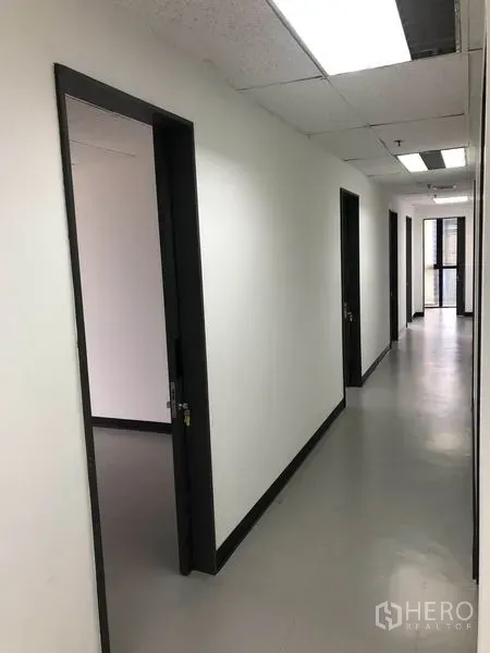 สำนักงาน ให้เช่าในWatthana, Bangkok - ทางเดินยาวเชื่อมห้องทำงานหลายห้อง พร้อมฝ้าเพดานไฟแบบกริด.