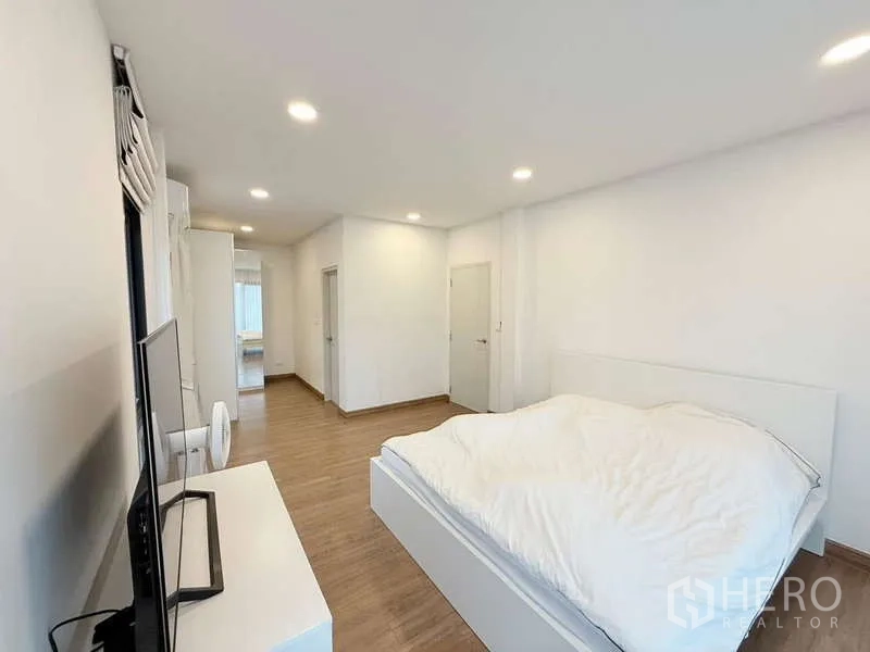 Detached House for sale in Bang Phli, Samut Prakan - Master bedroom with wood flooring, bed, TV and sliding door to balcony.
