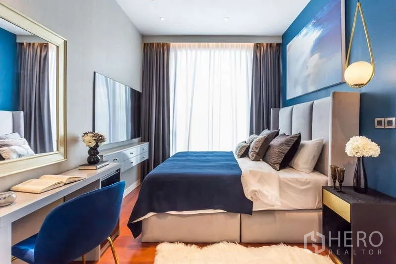 公寓 出租在Watthana, Bangkok - 卧室配蓝色强调墙、软包床、书桌、壁挂电视与高窗。