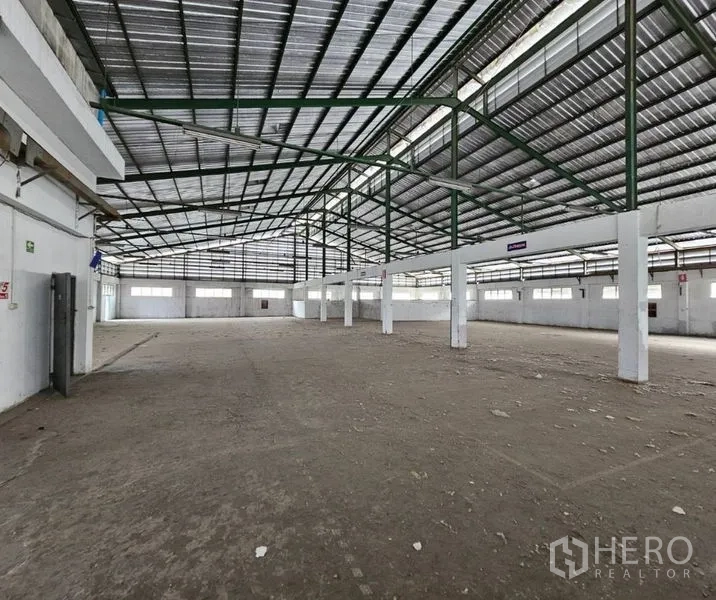 工厂 出租在Bang Kho Laem, Bangkok - 高挑棚厂房，绿色桁架梁与明亮周边窗户。