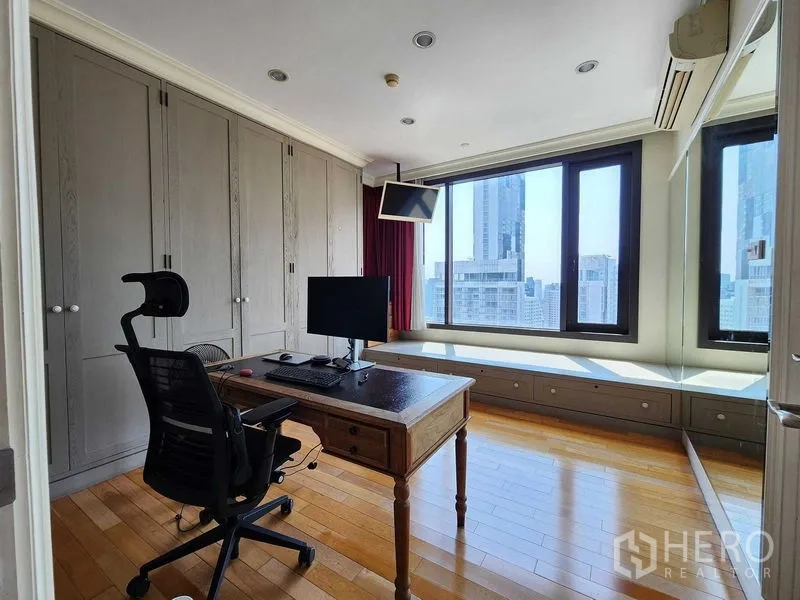 Condominium for sale in Khlong Toei, Bangkok - Home office with desk, ergonomic chair and full-height wardrobes by large windows.