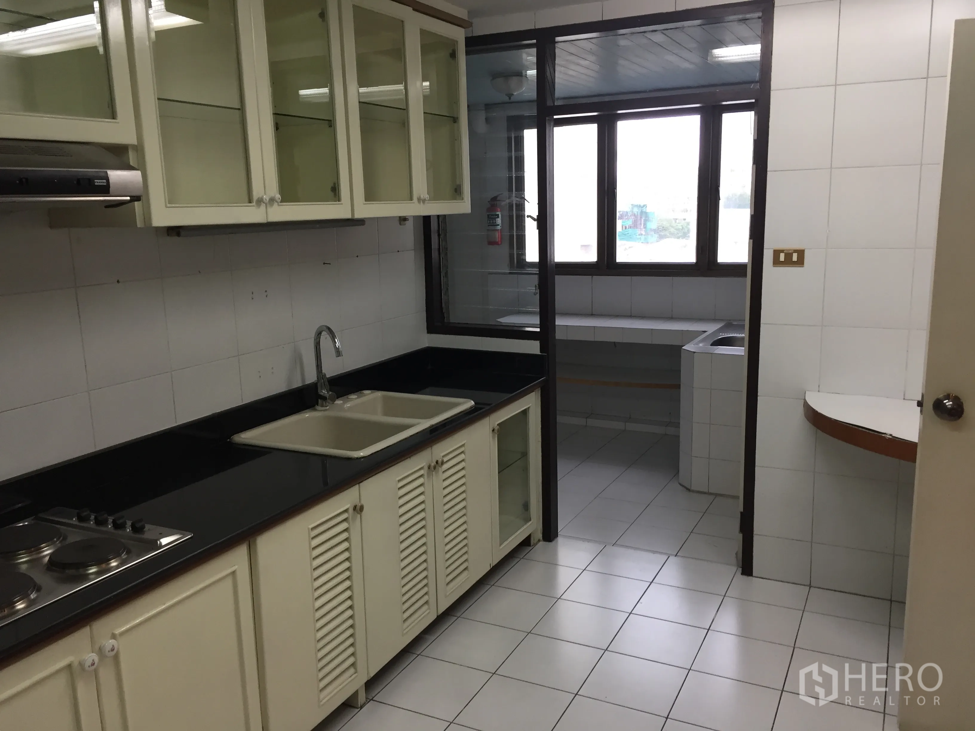 คอนโด ให้เช่าในWatthana, Bangkok - ครัวปิดเคาน์เตอร์สีดำ ตู้กระจก เตาไฟฟ้า และอ่างล้างจานคู่